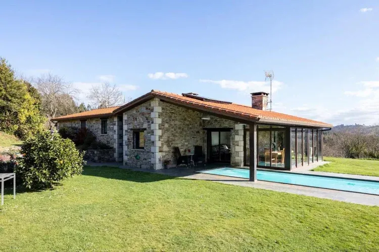 Imagen de Casa de piedra diseñada respetando la arquitectura típica de la zona. Piscina de 13 metros de longitud. Porche abierto sobre la piscina y porche cerrado de 18 m2 con ventanales correderas