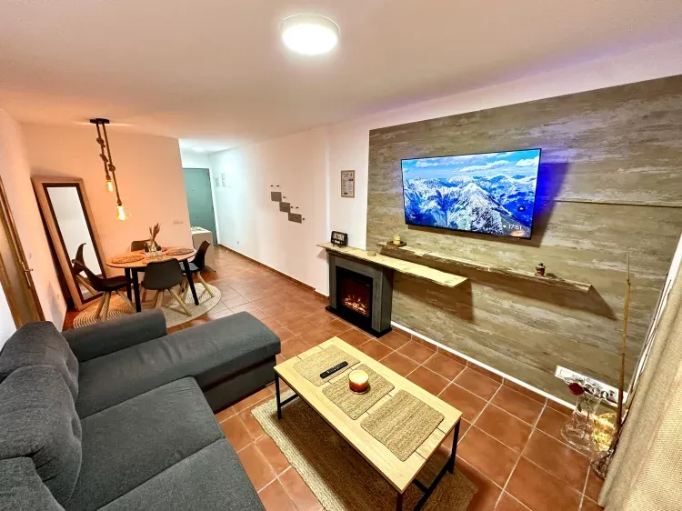 Imagen de Salón con aire acondicionado y chimenea eléctrica, acompañado por sofá cama dos plazas y Smart TV para ver tus películas y series favoritas. 