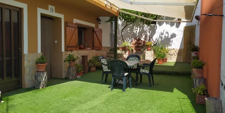 Imagen de Hermoso y florido patio con parra y entrada a la vivienda. 