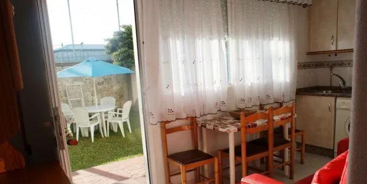 Imagen de Cocina equipada y mesa con sillas en el jardín al lado de la playa. Rodeiramar2A