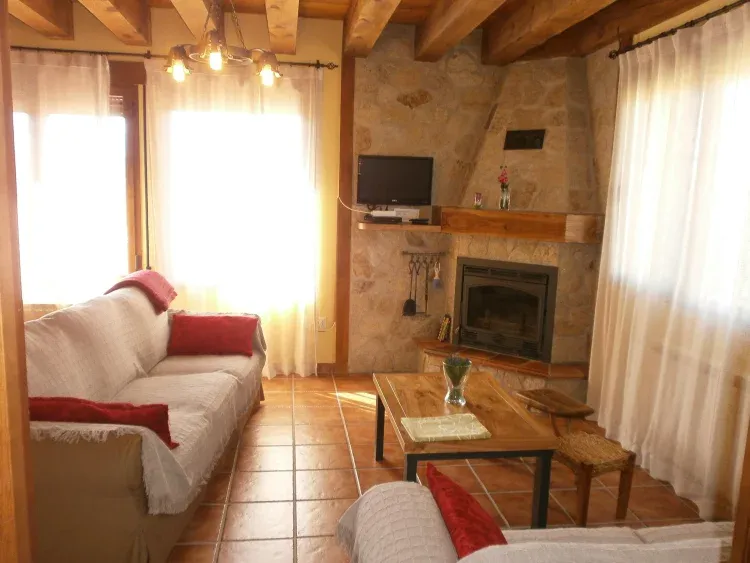 Imagen de zona de estar, con chimenea y dos amplios ventanales.