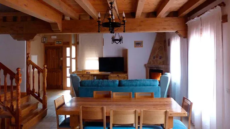 Imagen de Salón comedor con TV alta definición, libros, juegos, chimenea de leña, sofás y mesa para ocho comensales.