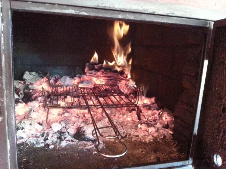 Imagen de Barbacoa y horno de leña, nevera, fregadero y mesa.