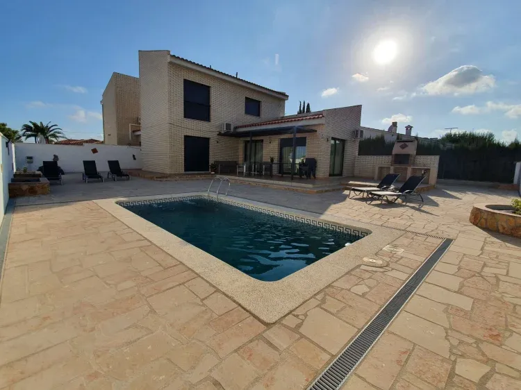 Imagen de Vista de fachada principal con jardín y piscina.