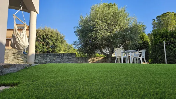 Imagen de Jardín que rodea la casa con césped artificial