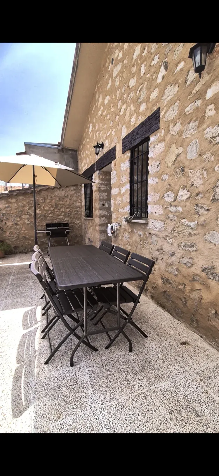 Imagen de patio privado con mesa sillas parasol y barbacoa