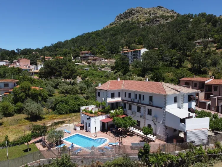 Imagen de Vista aerea de la casa rural El Batán. Se ve el patio trasero con la piscina y la montaña "Cabeza del Oso" al fondo.