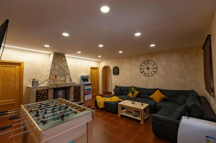 Imagen de Salón. Compuesto de sofá rinconera, mesa centro, chimenea, diana, futbolin, juegos de mesa, máquina retro de videojuegos, smart tv con Netflix, aire acondicionado, calefacción,detector de humos, mosquitera.