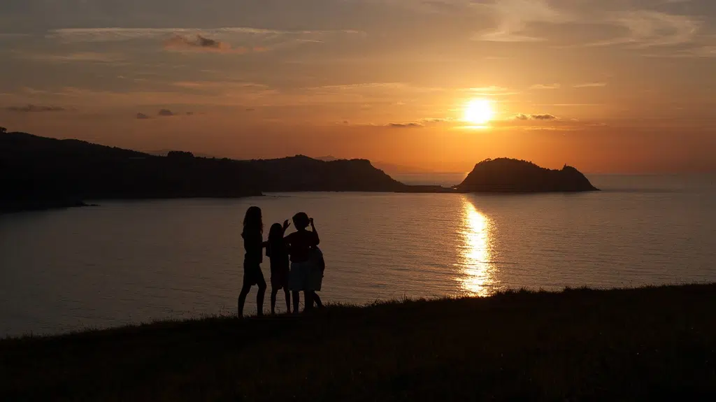 Siluetas de tres niños en la puesta del sol en la playa de Zarautz